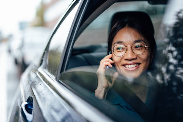 улыбающаяся азиатская женщина в машине звонит по телефону. - mobile phone seat belt text messaging smiling стоковые фото и изображения