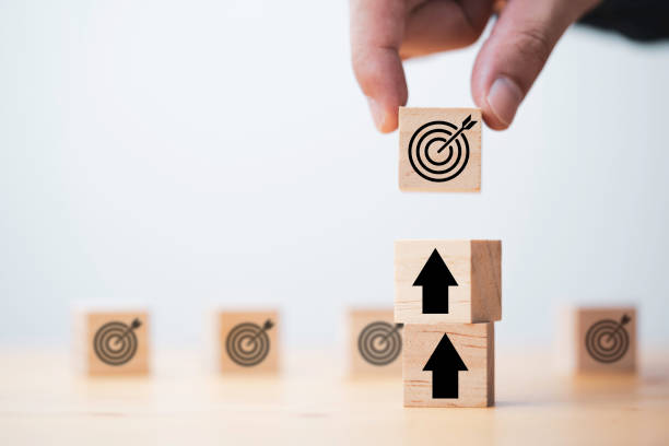 istock Businessman holding wooden cube block which print screen target board and lay down on up arrow block for enhance setup new challenges business objective concept. 1349189629