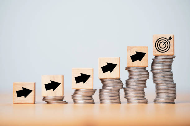 istock Target dartboard and up arrow print screen to wooden cube block on increasing coins stacking for enhance setup new challenges business objective concept. 1349190411