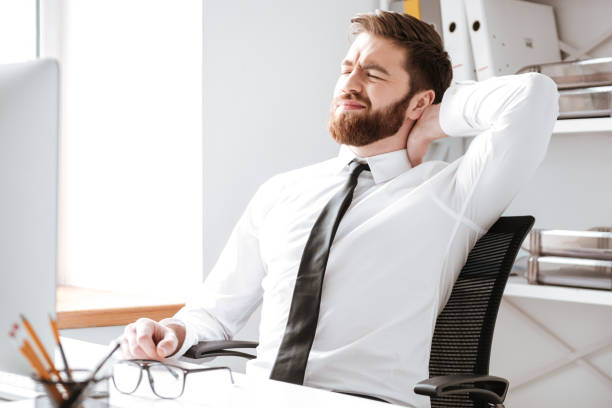 istock Tired young businessman in office stretching. 1349191353