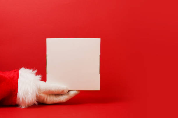 istock Santa Claus holding and offering a white gift box on his hand. red background with copy space, christmas delivery 1349191486