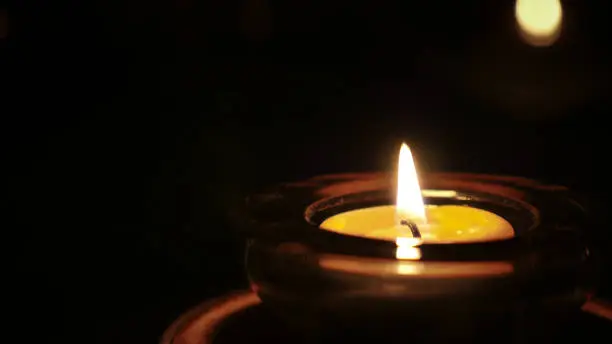 Small tea light candle burns in dark winter night