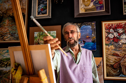Senior creative art and craft professional painting an artwork in his art studio