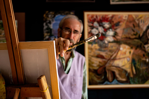 Senior creative art and craft professional painting an artwork in his art studio