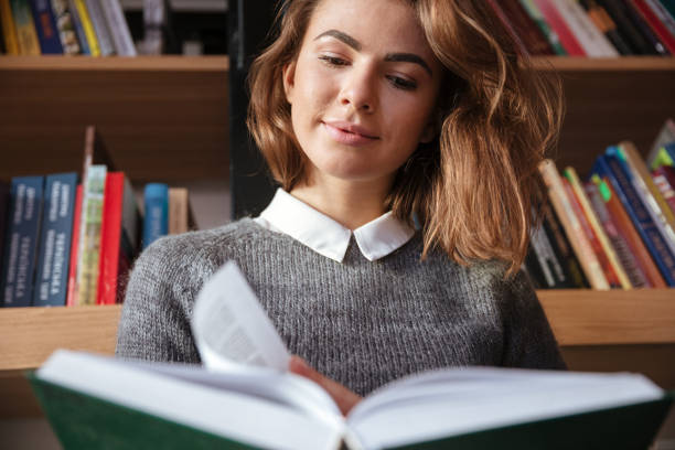 istock Girl reading book sitting on floor at library 1349197742