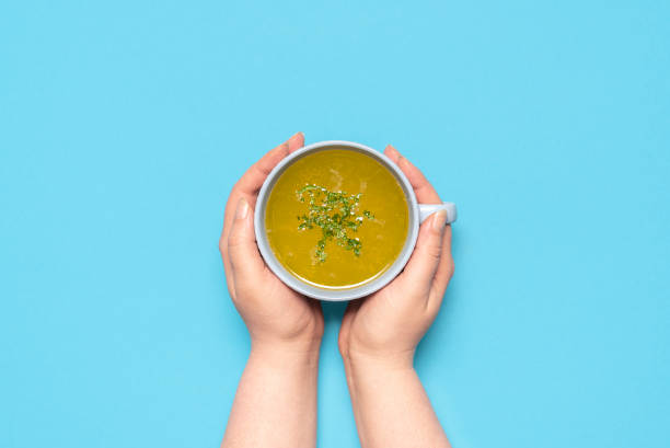 Chicken soup in a mug on a blue table, above view