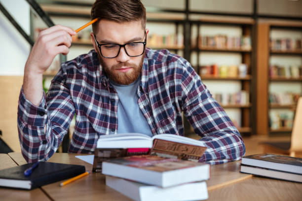 istock Serious young male student studying at desk in the library 1349198487