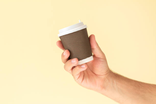 istock Man hand holding paper coffee cup with white plastic cap 1349199167