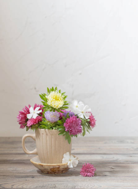 istock beautiful flowers in cup on wooden table on background white wall 1349200628