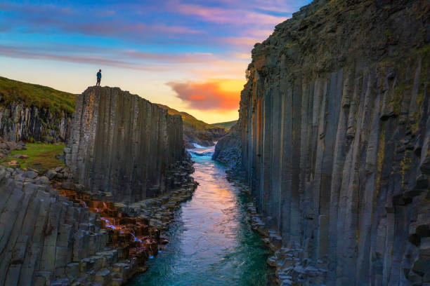 excursionista de pie en la cima del cañón studlagil en islandia al atardecer - natural column fotografías e imágenes de stock