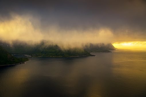 Aerial view of fog covered mountains on Senja island in Norway with Atlantic Ocean photographed at sunset