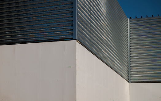 Closeup of white wall and metal wall against blue sky
