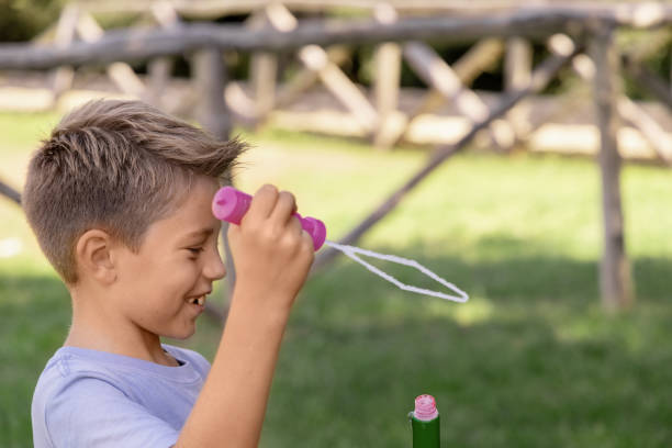istock Happy kid boy blowing soap bubbles in a park 1349204583