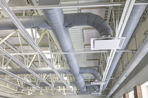 Exposed modern heating and cooling ductwork in the ceiling of a public school.