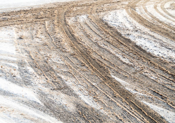 A snow covered road surface marked by multiple car tyres.