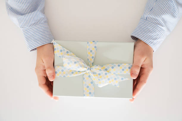 istock Flat lay of beautiful wrapped present box and hands holding gift box on white background 1349208395