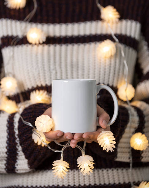 istock women hand holding white ceramic coffee cup with light decoration. mockup mug for creative advertising text message or promotional content. 1349209745