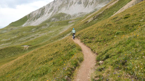 istock Woman mountain bikes along sunny mountain ridge 1349211887