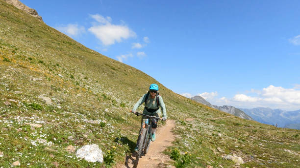 istock Woman mountain bikes along sunny mountain ridge 1349211970