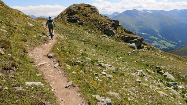 istock Woman mountain bikes along sunny mountain ridge 1349212249
