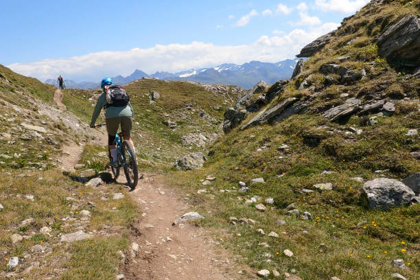 istock Woman mountain bikes along sunny mountain ridge 1349212276