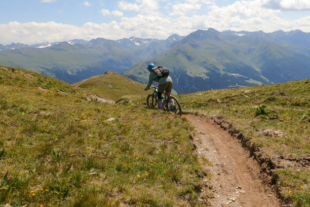 istock Woman mountain bikes along sunny mountain ridge 1349212357