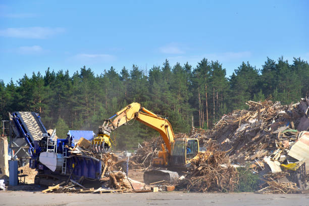 istock Excavator with log grab crane loads round logs in woodchipper. 1349214679