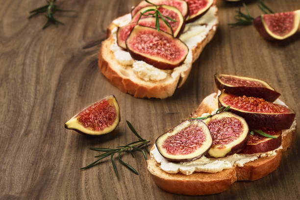 istock Wheat bread toast with figs and ricotta cheese on a wooden backdrop, closeup view, selective focus. Healthy food 1349217138