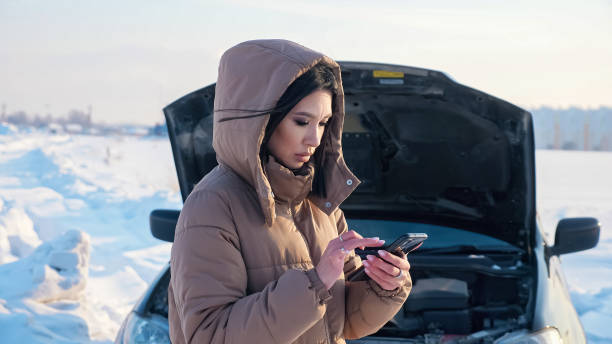 frau mit telefon wartet auf abschleppwagen in der nähe von kaputtem auto - emergency sign winter driving emergency services stock-fotos und bilder