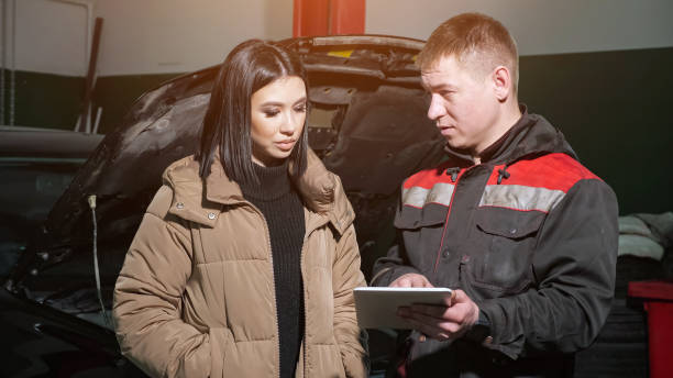 técnico muestra lista de precios en tablet al cliente en la estación - auto repair shop mechanic digital tablet customer fotografías e imágenes de stock