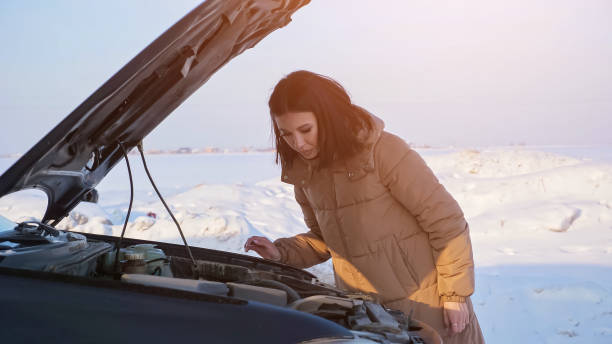 lady schaut auf motor eines kaputten autos auf verschneite straße - emergency sign winter driving emergency services stock-fotos und bilder