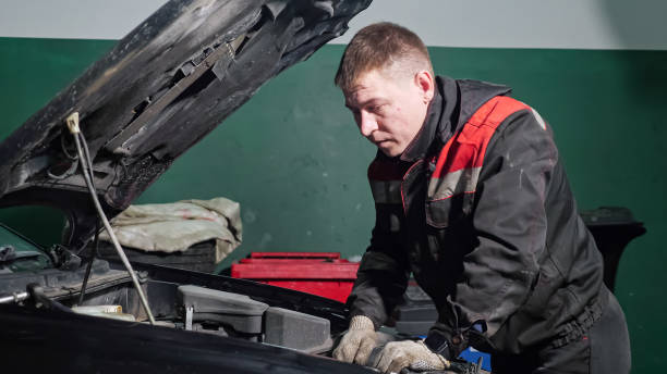 istock Young worker in uniform examines to fix broken automobile 1349218086