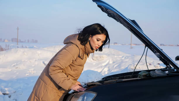 lady schaut auf motor eines kaputten autos auf verschneite straße - emergency sign winter driving emergency services stock-fotos und bilder