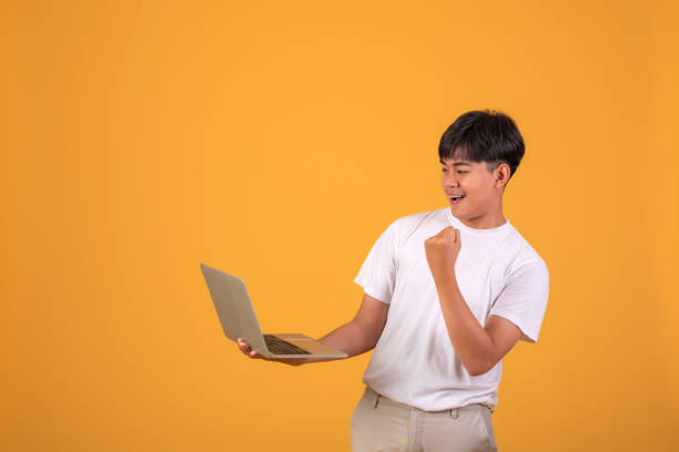 istock Asian man holding looking a laptop on orange background. 1349218167