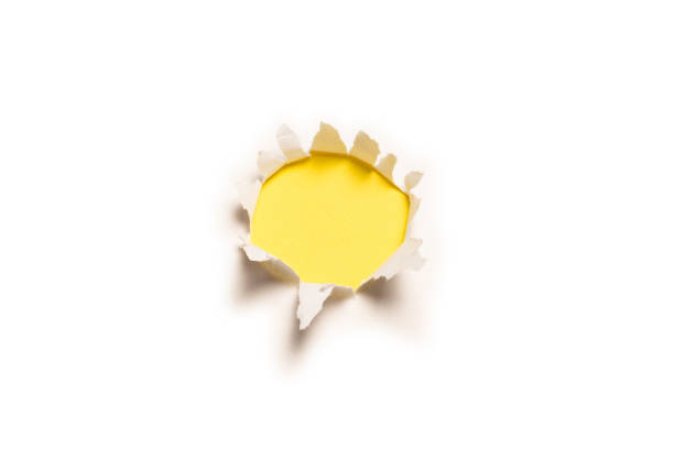 istock A hole in a white paper on a yellow background. 1349220977