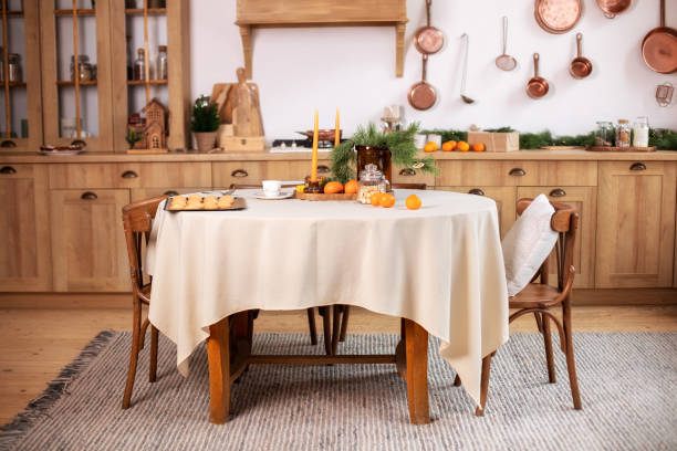 istock Interior design scandinavian kitchen with round table and chairs. Stylish dining room in rustic style. Cozy Wooden kitchen decorated Christmas or new year. On table fir branche in vase, Xmas cookies 1349221040