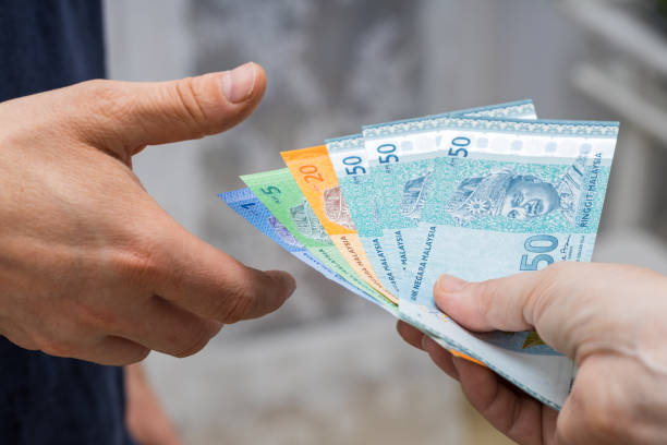 un file di denaro malese, ringgit, dato a un'altra persona di mano in mano - malaysian ringgit foto e immagini stock