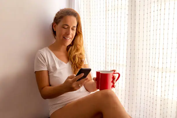 woman drinking coffee and texting. Copy space.