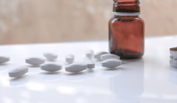 istock white pills on white blurred background having bottle 1349223614