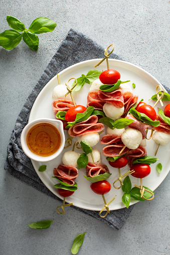 Italian style appetizer, antipasto skewer or caprese on a stick with basil, salami, mozarella and tomatoes
