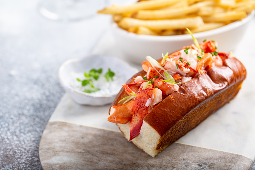 Lobster roll on a brioshe bun with fries on a marble board