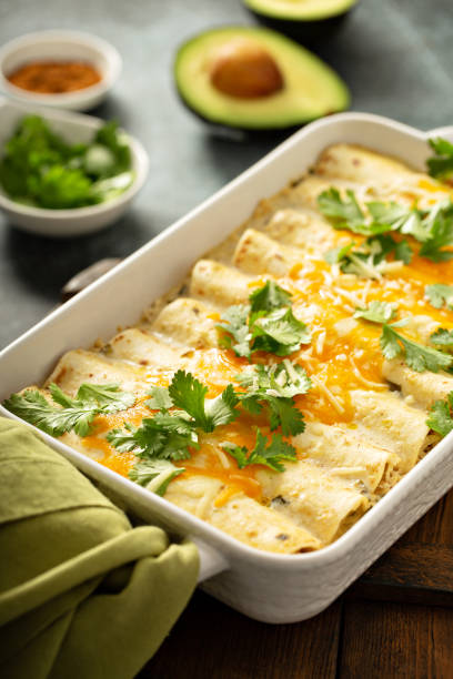 Green enchiladas casserole in a baking dish Green enchiladas casserole in a baking dish topped with cheese and cilantro enchilada stock pictures, royalty-free photos & images