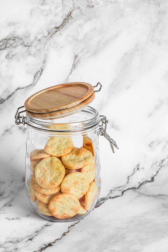 Delicious homemade cheddar cheese cracker in a glass jar on a light background