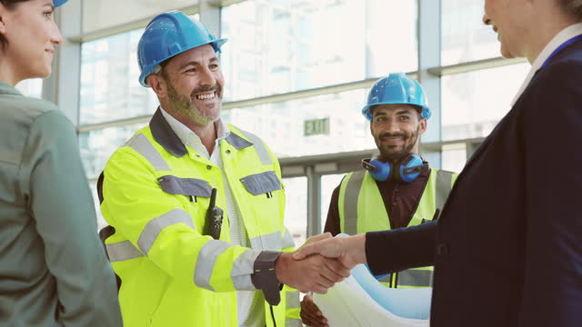Mature architect and contractor shaking hands at construction site