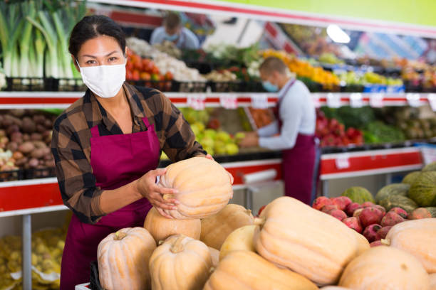istock Saleswoman in protective mask working in fruit and vegetable store 1349229270