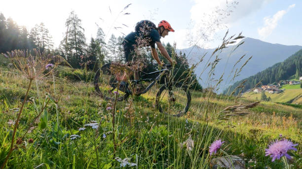 istock Man mountain bikes down grassy mountain slope 1349229663