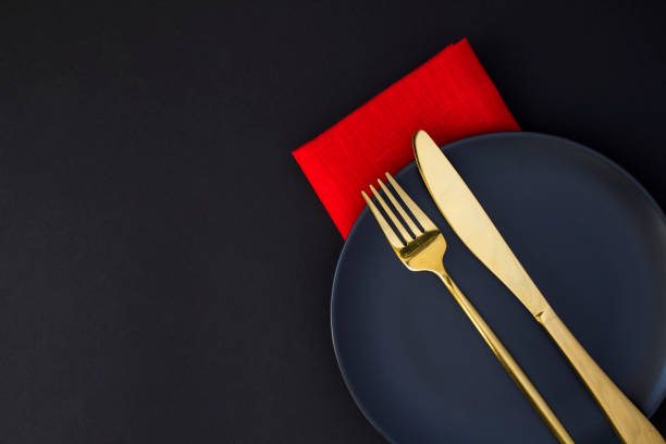 istock Festive table setting with gold knife and fork on the black plate on the black background. Top view. Copy space. 1349232961
