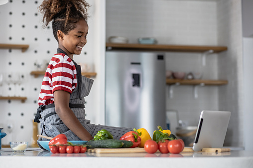 Young girl ready to prepare a meal while watching online tutorial on the tablet