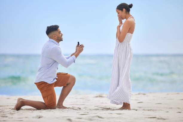 해변에서 그의 여자 친구에게 제안 하는 젊은 남자의 샷 - 약혼식 뉴스 사진 이미지