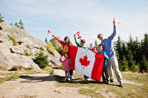 ハッピーカナダデー。山の中で大きなカナダの旗のお祝いを持つ家族。 - カナダデー ストックフォトと画像